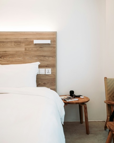 A white comforter and pillows on a bed with a wooden headboard