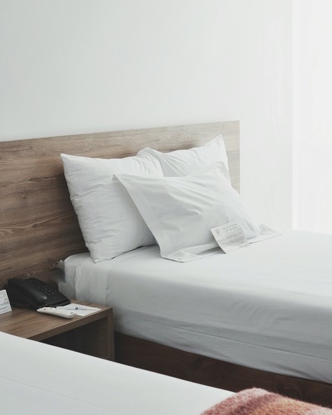 Twin beds dressed in white pillow covers and sheets