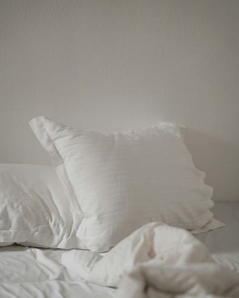 White pillows with a fine stripe on a white bed